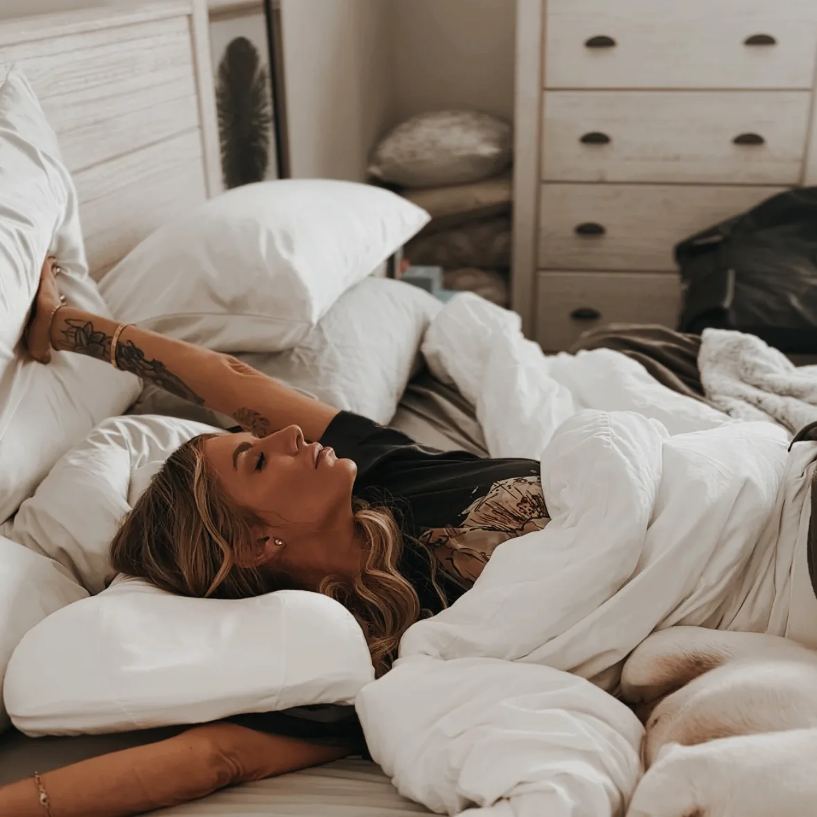 Danielle Keasling stretching in bed among white pillows